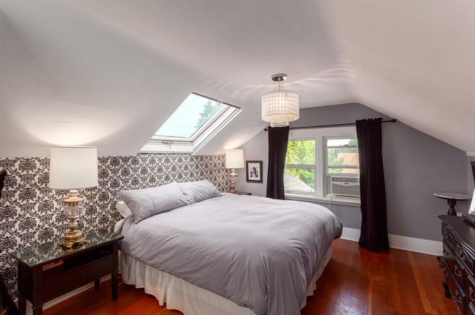 Upper bedroom after renovation — patterned feature wall, crystal pendant and dark drapery