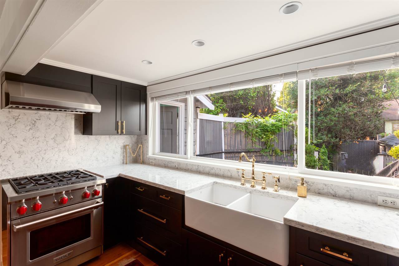 Kitchen after renovation — marble backsplash, farmhouse sink with brass fittings and professional range