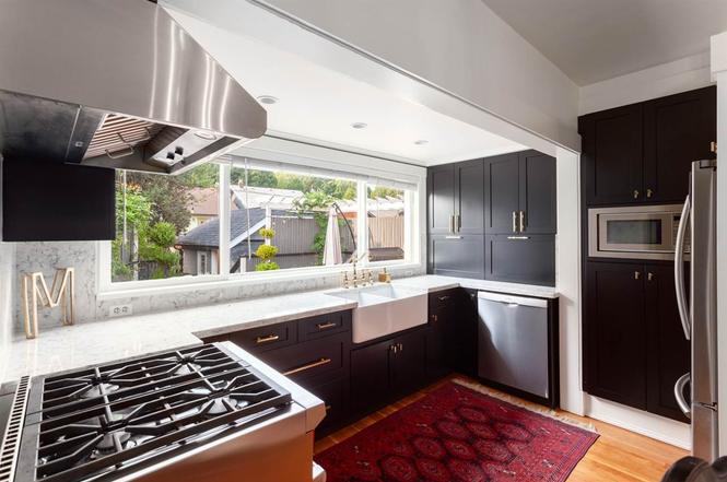 Kitchen after renovation — dark shaker cabinetry, stone counters and stainless appliances