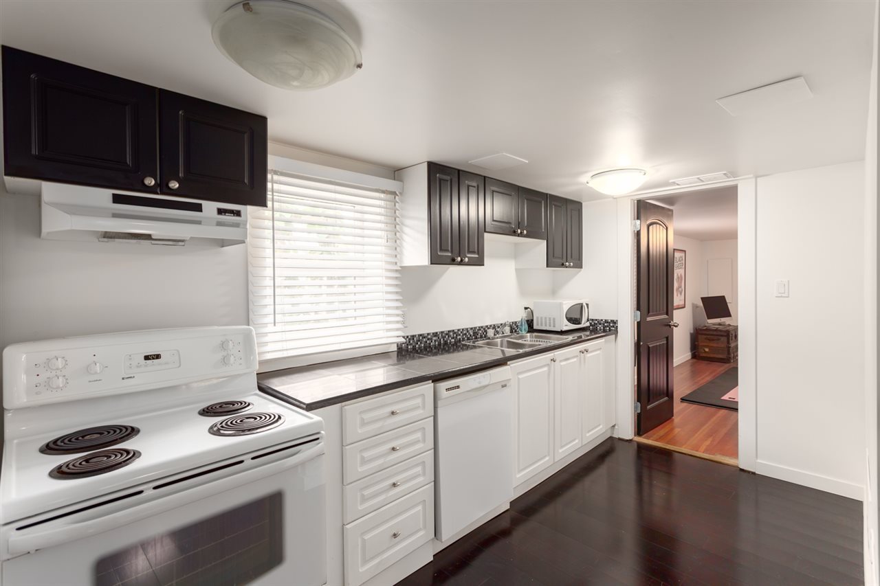 Lower kitchen after renovation — galley layout with dark upper cabinets and dark hardwood floor