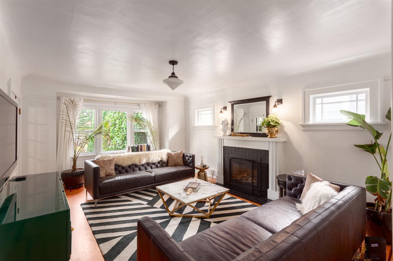 Living room after renovation — black tiled fireplace with white mantel, leather chesterfields and graphic rug