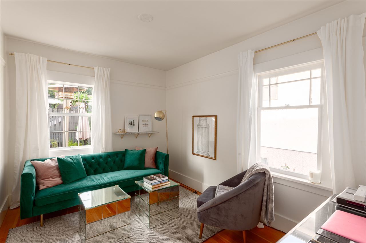 Sitting room after renovation — white walls, full-length curtains and emerald velvet sofa