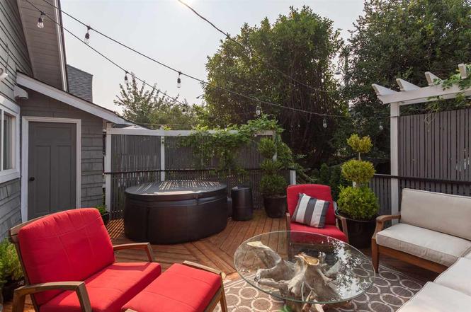 Rear yard after renovation — cedar deck with hot tub, festoon lighting and privacy screening at dusk