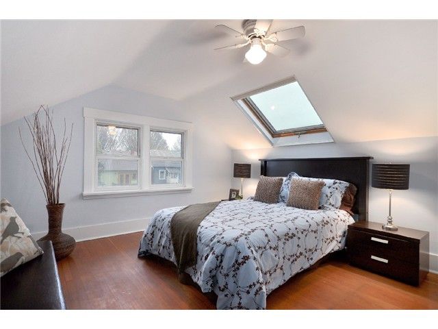Upper bedroom before renovation — plain walls, ceiling fan and skylight under a sloped ceiling