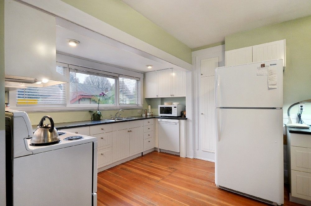 Kitchen before renovation — green walls, white laminate cabinets and dated appliances