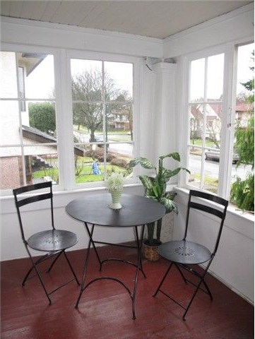 Enclosed front porch before renovation — painted red floor and bistro table